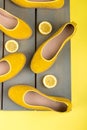 Yellow espadrilles shoes near slices of lemon on wooden background. Top view.
