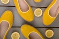 Yellow espadrilles shoes near slices of lemon on wooden background. Top view.