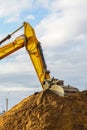 A yellow excavator boom with a bucket digs a pile of earth Royalty Free Stock Photo