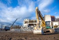 Yellow excavator with bucket at demolition of tall building. Hydraulic machine for demolish. Backhoe destroys concrete of the old Royalty Free Stock Photo