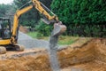 A yellow excavator bucket shovel moving stones gravel of foundation on a construction site Royalty Free Stock Photo