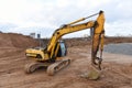 Yellow Excavator at building under construction. Backhoe digs the ground for the foundation and for laying sewer pipes