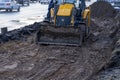 Yellow excavator, bulldozer and working tractor. Road works in the city center.