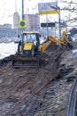 Yellow excavator, bulldozer and working tractor. Road works in the city center.