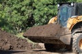 Yellow excavator collects earth in a big pile background without people