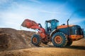 Yellow excavator on a construction site against blue sky. wheel loader at sandpit during earthmoving works Royalty Free Stock Photo