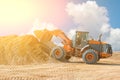 Yellow excavator on a construction site against blue sky. wheel loader at sandpit during earthmoving works Royalty Free Stock Photo