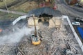 Yellow excavator destroys building. Heavy duty machine is demolishing a brick building. Demolition of the building . Demolition