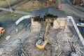 Yellow excavator destroys building. Heavy duty machine is demolishing a brick building. Demolition of the building . Demolition