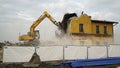 Yellow excavator destroys building. Heavy duty machine is demolishing a brick building. Demolition of the building . Demolition