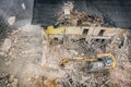 Yellow excavator destroys building. Heavy duty machine is demolishing a brick building. Demolition of the building . Demolition