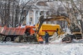 A yellow excavator digs a hole to eliminate an accident on the utility pipelines in the city in winter. Workers