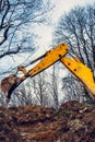A yellow excavator in the forest digs a pit for a pond Royalty Free Stock Photo