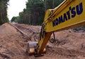 Yellow excavator KOMATSU during earthwork for laying Crude oil and Natural gas pipeline in forest area. Installation Petrochemical