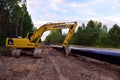 Yellow excavator KOMATSU during earthwork for laying Crude oil and Natural gas pipeline in forest area. Installation Petrochemical