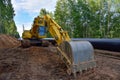 Yellow excavator KOMATSU during earthwork for laying Crude oil and Natural gas pipeline in forest area.