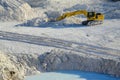 Yellow excavator in limestone quarry