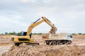 Yellow excavator machine loading soil into a dump truck at construction site Royalty Free Stock Photo