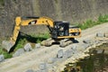 Yellow excavator machine works near Arno river shores, in Florence