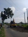 Yellow excavator in the middle of the road clearing lumps of material Royalty Free Stock Photo