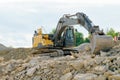 A yellow excavator on a pile of gravel