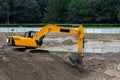 yellow excavator shovels sand with a bucket