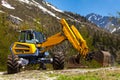 Yellow excavator working near mountains