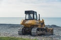 Yellow excavator working on the pebbled beach near the seashore. Royalty Free Stock Photo