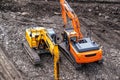 A yellow excavator works in the mountains. Construction of roads