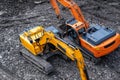 A yellow excavator works in the mountains. Construction of roads