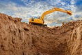 Yellow excavators are digging the soil in the construction site on the sky and cloud background. Royalty Free Stock Photo