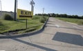 Yellow exit sign outdoors pointing towards an empty roadway Royalty Free Stock Photo