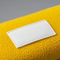 Yellow fabric with a textured surface holds a rectangular white patch, stitched with cle Royalty Free Stock Photo