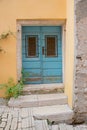 Yellow facade and blue door with exfoliated paints and weathered stairs