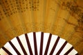 Yellow fan with brown chinese characters on it, white background, closeup Royalty Free Stock Photo