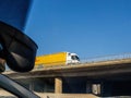 yellow fast DHL truck driving on a bridge above autobahn - low angle view from a