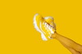 Yellow female sneakers on long woman legs isolated on yellow background. Monochrome pop art concept Royalty Free Stock Photo