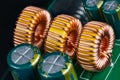 Yellow ferrite cores of toroidal inductors wrapped with copper wire on green printed circuit board
