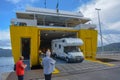 Yellow ferry just arrived in port of Elba island in Italy. White RV drives out, two passengers waiting. Transportation via sea