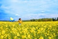 Yellow field with blooming rapeseed, a girl runs with balloons. The concept of freedom and summer.Yellow and blue Royalty Free Stock Photo