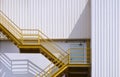 Yellow fire escape on white corrugated steel wall outside of industrial building Royalty Free Stock Photo