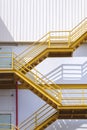 Yellow fire escape on white corrugated steel wall outside of industrial building in vertical frame Royalty Free Stock Photo