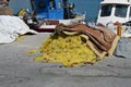 Yellow fishing net with red-brown floats piled on pavement in port of Heraklion. Royalty Free Stock Photo
