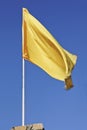 Yellow flag fluttering in blue sky Royalty Free Stock Photo