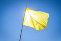 Yellow flag fluttering in deep blue sky in between the bright sun and the viewer Royalty Free Stock Photo