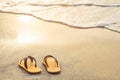 Yellow flip flop on the beach with bright light of sunset in summer