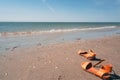 Yellow flip flop on the beach. Summer holidays concept. Sandals, sand, sea, blue sky with bright light of sunset in summer Royalty Free Stock Photo