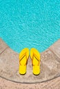 Yellow Flip Flops at the edge of a swimming pool deck Royalty Free Stock Photo
