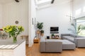 Flowers on the counter in open space living and dining room interior with grey lounge furniture