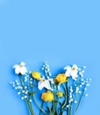 Yellow flowers of trolius europaeus, white daffodils and lilies of the valley on a blue background. Bright color. Background for